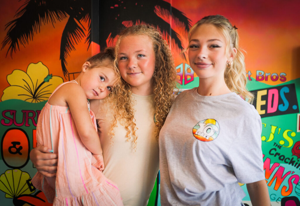 A group of children together in front of the Yo Coast surf mural