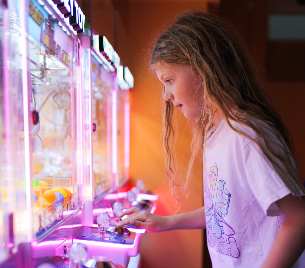 A child playing a claw machine in the Yo Coast arcade