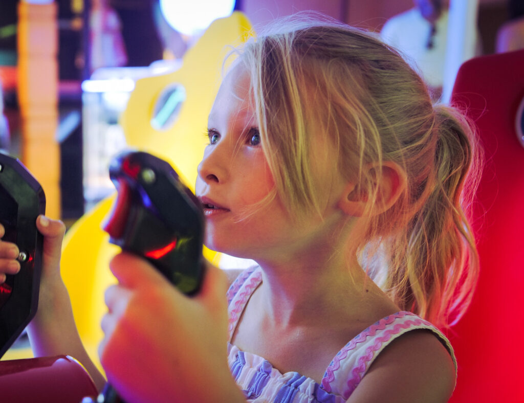 A girl concentrating as she plays an arcade driving game