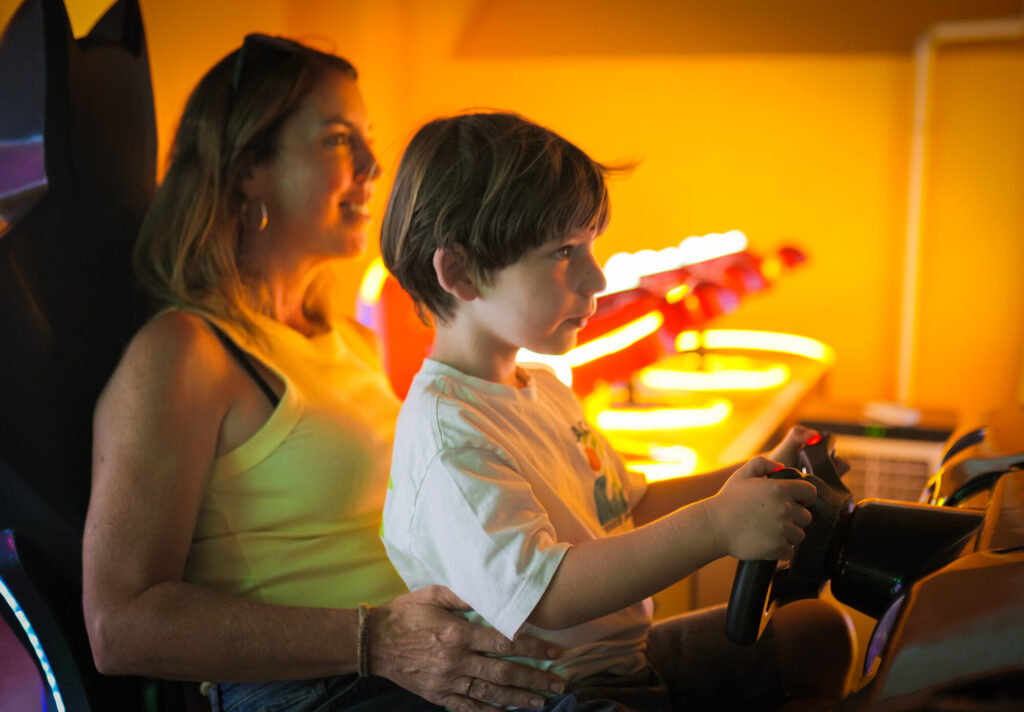 A parent and child playing a racing arcade game together